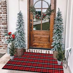 two christmas trees are on the front porch with plaid rugs and potted plants