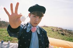 a young man wearing a hat and bow tie making the peace sign with his hand