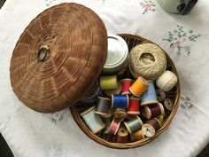 a basket filled with spools of thread next to a cup on a table