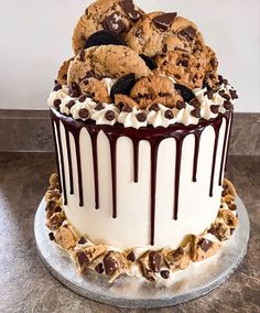 a cake with chocolate chip cookies and white frosting on top is sitting on a table