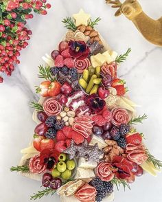 a christmas tree made out of fruits and cheeses on a marble countertop next to a gold bird