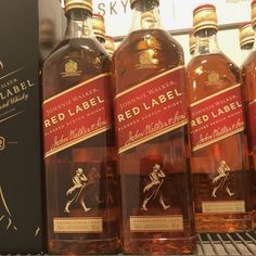 bottles of red label whisky on display in a store