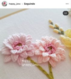 two crocheted flowers sitting on top of a table