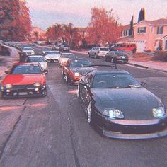 cars are parked on the side of the road in front of some houses and trees