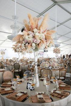 a tall vase filled with lots of flowers sitting on top of a table covered in plates and napkins