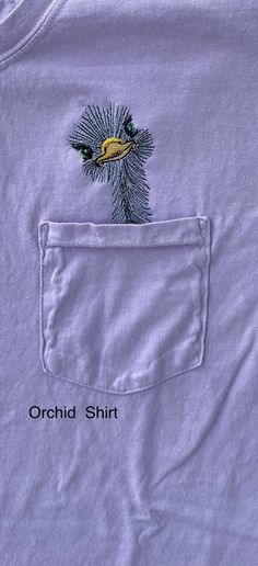 an embroidered t - shirt with a bird on it's back pocket