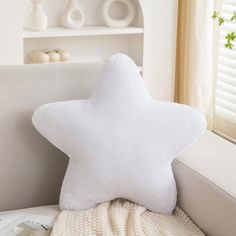 a white star shaped pillow sitting on top of a couch next to a book shelf