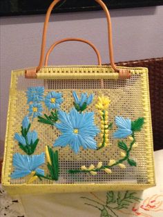 a yellow purse with blue flowers on it sitting on a table next to a painting