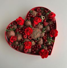 a heart shaped box filled with chocolates and flowers