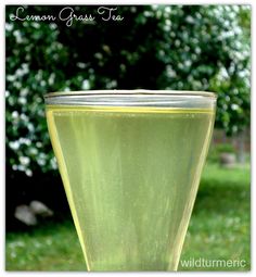 a glass filled with liquid sitting on top of a green field