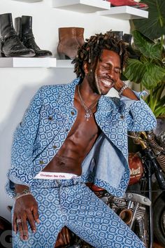 a man with dreadlocks sitting on a motorcycle in front of a shelf full of shoes