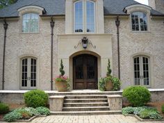 the front entrance to a large home with steps leading up to it and potted plants on either side