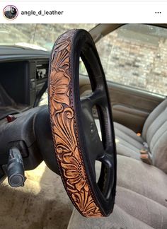 the inside of a car with an intricate leather steering wheel cover