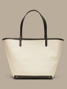 An elegant companion to everyday style, this classic tote goes anywhere with ease with spacious storage, sturdy leather trim, and a snap closure.  Sturdy leather handles.  Open top with snap closure.  Height: 16" (41cm) Width: 25" (63cm) Depth: 8" (2 Large Capacity Coated Canvas Bucket Bag For Shopping, Classic Coated Canvas Shoulder Bag, Canvas Bucket Bag With Leather Handles For Everyday Use, Classic Shoulder Bag With Leather Trim, Rectangular Coated Canvas Bucket Bag With Leather Handles, Classic Bucket Bag With Leather Handles, Everyday Duck Canvas Shoulder Bag With Double Handle, Classic Coated Canvas Bucket Shoulder Bag, Leather Canvas Tote Bag With Handles