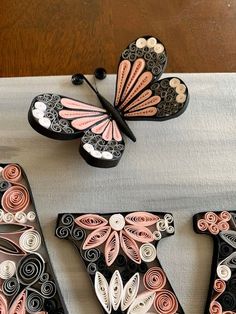 three butterflies are sitting on top of some type of letter made out of wood and paper