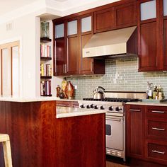 a kitchen with wooden cabinets and stainless steel appliances in the center, along with a bar stool