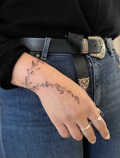 a woman's hand with a flower tattoo on her left wrist and the other arm