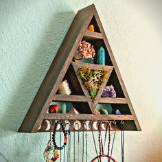 a triangle shaped shelf with jewelry hanging from it's sides