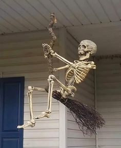 a skeleton hanging from the side of a house with a broom in it's hand