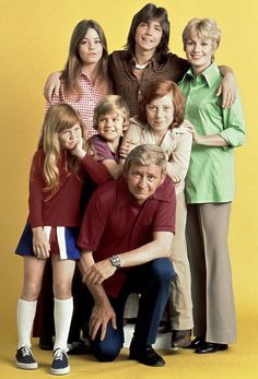 the cast of modern family poses for a portrait in front of a yellow background with their arms around each other