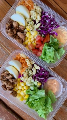 two plastic containers filled with food on top of a wooden table next to each other