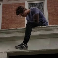 a man sitting on top of a window sill