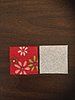 an open book on a wooden table with a red and white flowered cover next to it