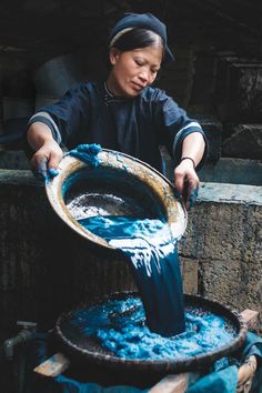 a woman is pouring water into a bucket