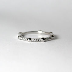 a white gold ring with small diamonds on it's sides, sitting on a table