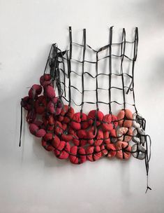 a bunch of red and white balls hanging from a wire net on the wall,