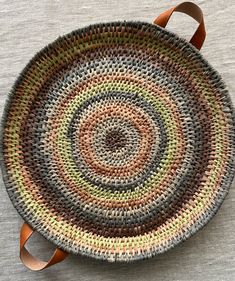 a woven basket with leather handles is shown on the floor, next to a gray table cloth