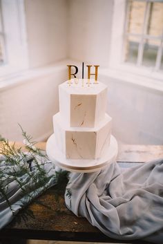 a three tiered white cake sitting on top of a table next to a window