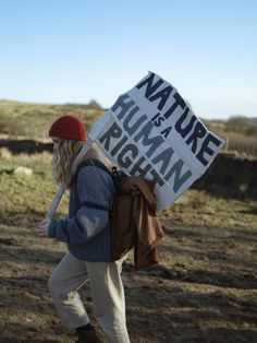 a woman carrying a sign that says nature is human rights in the middle of nowhere