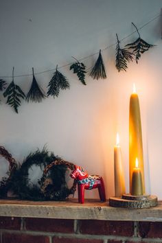 a lit candle sitting on top of a mantle next to a wreath and other decorations