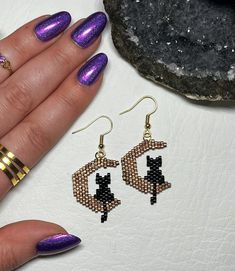 These hand-beaded earrings are a fun accessory for spooky season but are dainty and neutral enough to be worn all year long. Perfect gift for any cat mom in your life.  Made with high quality duracoated Miyuki beads that won't chip or fade, jewelry-grade thread and gold coated ear wires. Each pair comes with silicone earring backings.  ** Silver option will have silver moons and matching sterling silver ear wires. Length: 2 inches Width: 1 inch If you would like your cat to be made in a different solid color, please send me a message. I'd love to make a custom pair just for you! Cute Black Dangle Jewelry, Party Jewelry With Cat Design And Cat Ears, Party Jewelry With Cat Design, Handmade Bohemian Jewelry For Halloween, Black Cat Ears Jewelry For Gifts, Black Cat Ears Jewelry As A Gift, Handmade Dangle Halloween Jewelry, Handmade Witchy Earrings For Gift, Handmade Dangle Jewelry For Halloween