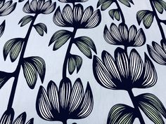 a black and white flower pattern on a plain fabric with green leaves in the background