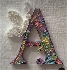 the letter a is made out of paper and has swirls on it, with a butterfly