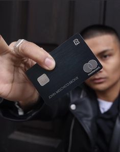 a man holding up a black credit card