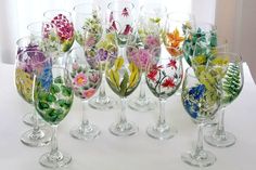 there are many wine glasses that have flowers in them on the table next to each other