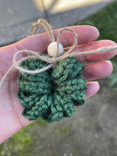 a hand holding a small green crochet flower