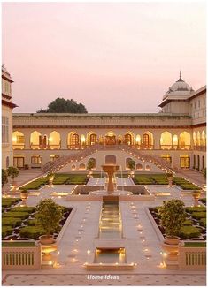 a large building with lots of plants and lights on it's front lawn area