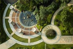 an aerial view of a circular building surrounded by greenery and trees, in the middle of a park