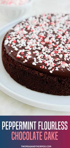 a chocolate cake with white and red sprinkles on top, sitting on a plate