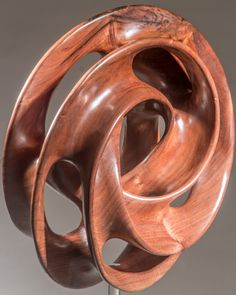 a wooden sculpture is shown on a metal stand with wood circles in the shape of spirals