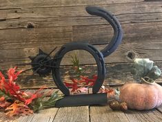 two pumpkins and an iron cat on a wooden table with autumn leaves around it