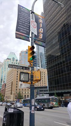 a traffic light sitting on the side of a road next to tall buildings with banners