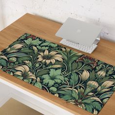 a laptop computer sitting on top of a wooden desk next to a flowery rug