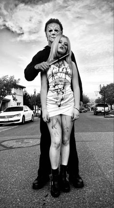 a man standing next to a woman on the street with her face covered in makeup