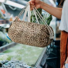 a woman is holding a leopard print bag