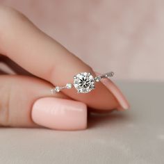 a woman's hand holding a diamond ring